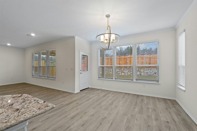 unfurnished dining area featuring an inviting chandelier, ornamental molding, and light hardwood / wood-style floors