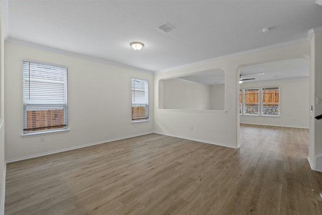 empty room featuring hardwood / wood-style flooring, crown molding, and plenty of natural light