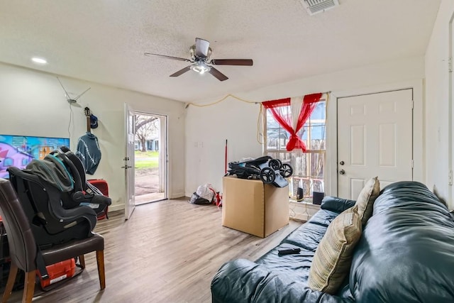 living room with ceiling fan, light hardwood / wood-style floors, and a textured ceiling