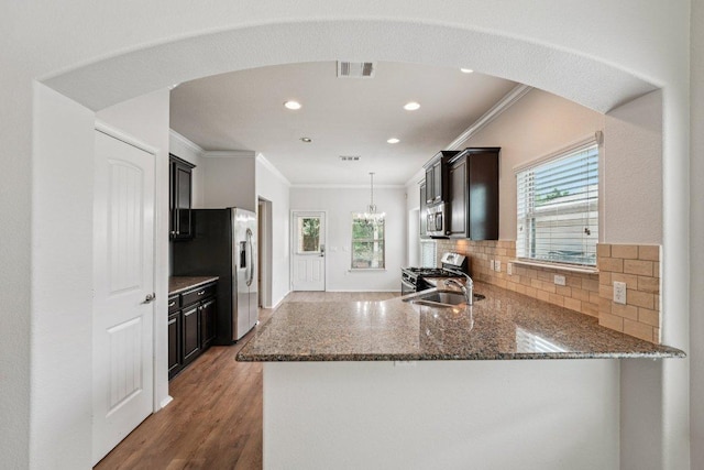 10017 Pinnacle Crest Loop, Austin, TX 78747 - kitchen featuring stainless steel appliances, crown molding, arched walkways, dark stone countertops, and backsplash