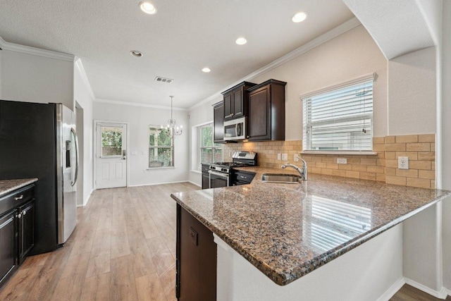 10017 Pinnacle Crest Loop, Austin, TX 78747 - kitchen with stainless steel appliances, stone counters, light wood finished floors, a chandelier, and a sink