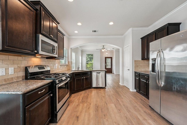 10017 Pinnacle Crest Loop, Austin, TX 78747 - kitchen with stainless steel appliances, arched walkways, a sink, light wood finished floors, and dark brown cabinets
