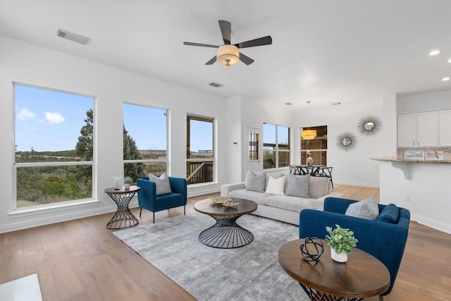 living room with ceiling fan, sink, and light hardwood / wood-style flooring