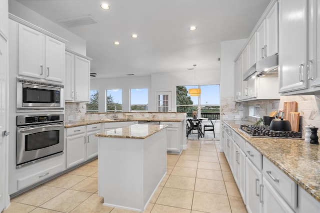 kitchen with stainless steel appliances, a center island, hanging light fixtures, and white cabinets