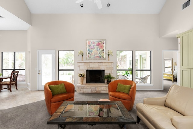 carpeted living room with ceiling fan, a towering ceiling, and a fireplace