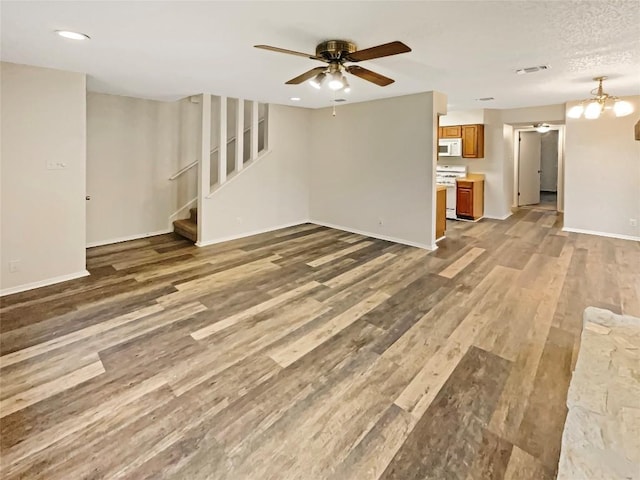 unfurnished living room with ceiling fan with notable chandelier and wood-type flooring