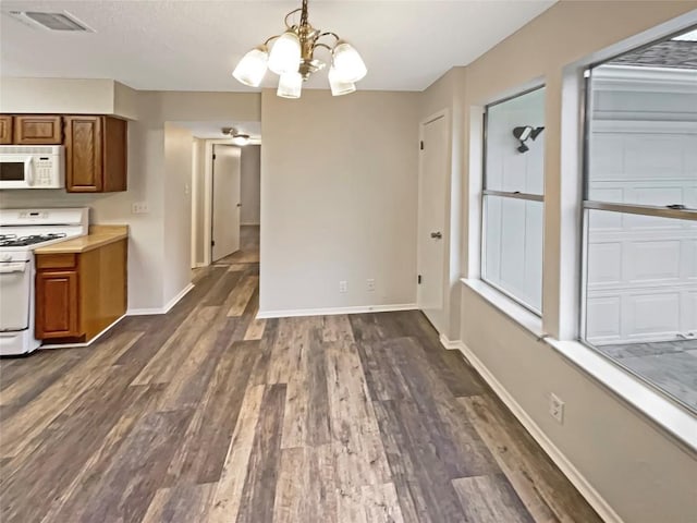 6234 Hillston Dr, Austin, TX 78745 - kitchen with white appliances, brown cabinets, a chandelier, and dark wood-style floors