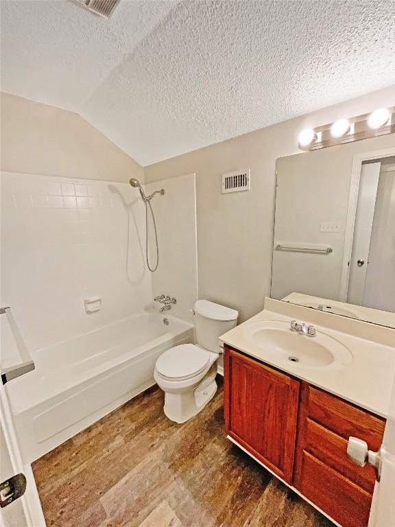 6234 Hillston Dr, Austin, TX 78745 - bathroom featuring wood finished floors, a textured ceiling, vanity, washtub / shower combination, and lofted ceiling