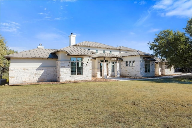 1821 Overland Stage Rd, Dripping Springs, TX 78620 - rear view of house featuring a standing seam roof, a chimney, a lawn, stone siding, and metal roof