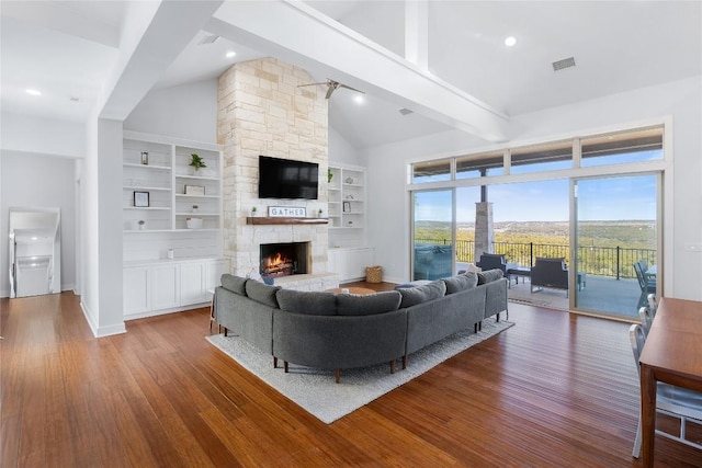 1821 Overland Stage Rd, Dripping Springs, TX 78620 - living area featuring wood finished floors, high vaulted ceiling, beam ceiling, a stone fireplace, and built in features