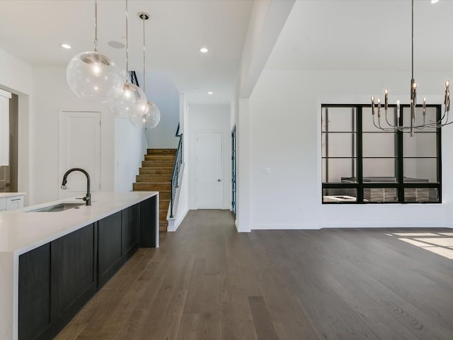 kitchen with a center island with sink, sink, pendant lighting, and dark hardwood / wood-style flooring