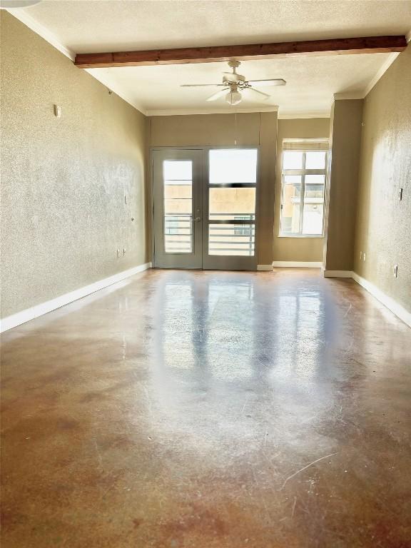 empty room with french doors, concrete flooring, a textured ceiling, ceiling fan, and beam ceiling