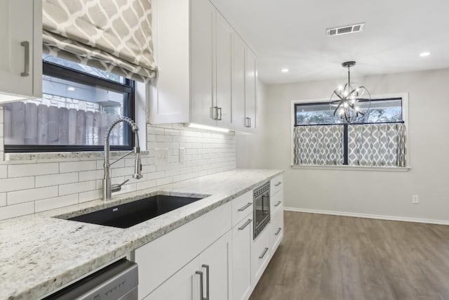 kitchen featuring sink, light stone counters, hanging light fixtures, stainless steel appliances, and white cabinets