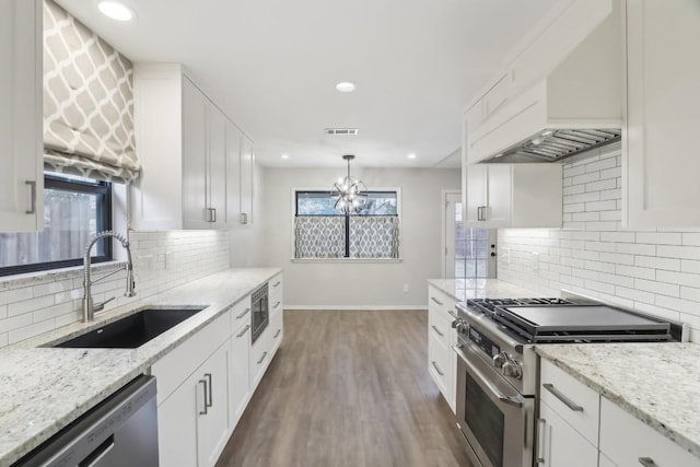 kitchen with premium range hood, sink, decorative light fixtures, appliances with stainless steel finishes, and white cabinets