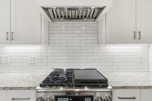 kitchen featuring stainless steel range, white cabinets, light stone counters, and wall chimney exhaust hood