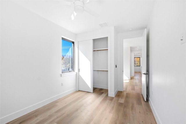 unfurnished bedroom featuring multiple windows, light hardwood / wood-style floors, and a closet