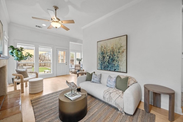 living room featuring ornamental molding, wood-type flooring, and ceiling fan