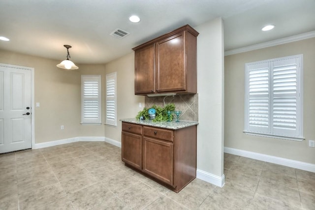 kitchen with backsplash, decorative light fixtures, light stone countertops, and light tile patterned floors