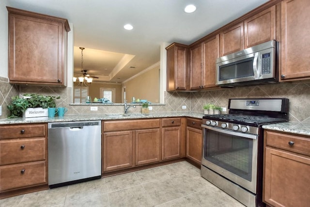 kitchen with stainless steel appliances, light stone countertops, sink, and backsplash