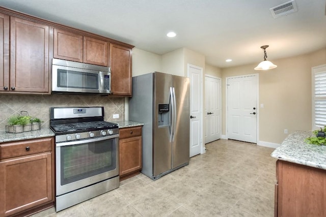 kitchen with hanging light fixtures, decorative backsplash, stainless steel appliances, and light stone countertops