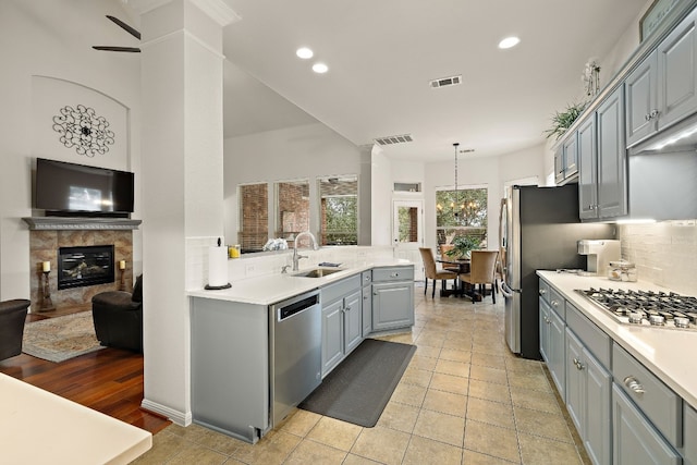 2621 Golden Gate Park, Austin, TX 78732 - kitchen with sink, appliances with stainless steel finishes, tasteful backsplash, a tiled fireplace, and decorative light fixtures