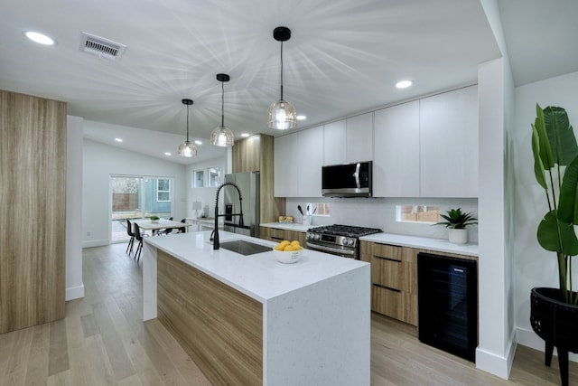 908 E 51st St, Austin, TX 78751 - kitchen featuring modern cabinets, stainless steel appliances, beverage cooler, a sink, and an island with sink