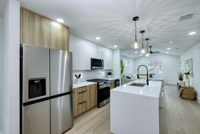 908 E 51st St, Austin, TX 78751 - kitchen featuring appliances with stainless steel finishes, a sink, modern cabinets, open floor plan, and an island with sink