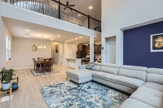 living room with hardwood / wood-style flooring, ceiling fan with notable chandelier, and a high ceiling