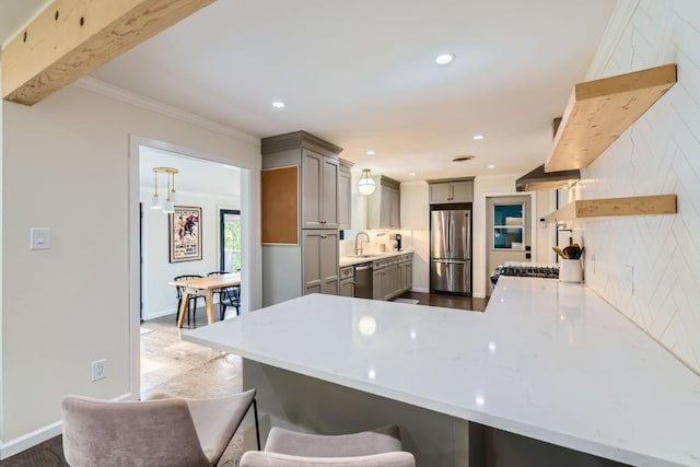 1713 Mariposa Dr, Austin, TX 78741 - kitchen featuring appliances with stainless steel finishes, gray cabinets, a peninsula, wood finished floors, and backsplash