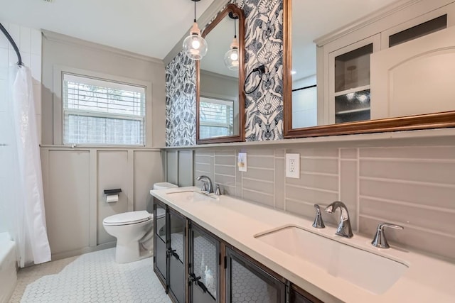 1713 Mariposa Dr, Austin, TX 78741 - bathroom featuring a decorative wall, ornamental molding, toilet, double vanity, and a wainscoted wall