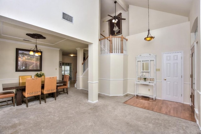 carpeted dining space featuring ceiling fan, high vaulted ceiling, and beamed ceiling