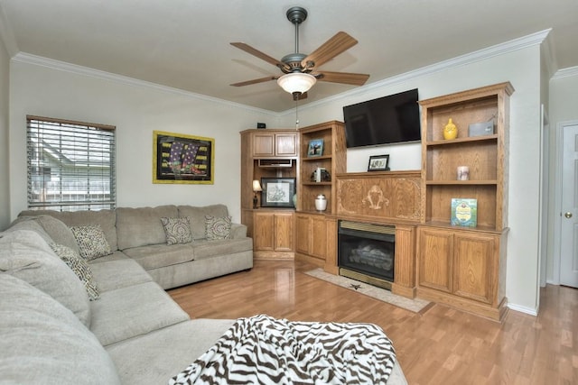 living room with ceiling fan, ornamental molding, a fireplace, and light wood-type flooring