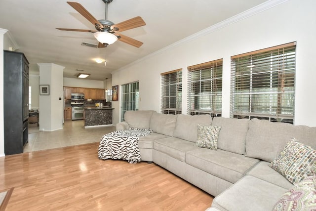 living room with ceiling fan, ornamental molding, light hardwood / wood-style flooring, and plenty of natural light