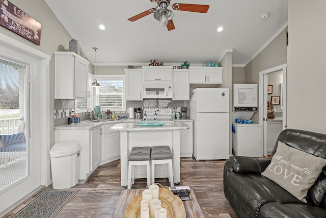 kitchen with vaulted ceiling, a kitchen island, a breakfast bar, white cabinetry, and white appliances