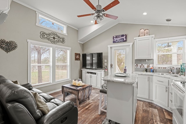 kitchen featuring white cabinetry, hanging light fixtures, a kitchen breakfast bar, a kitchen island, and stove