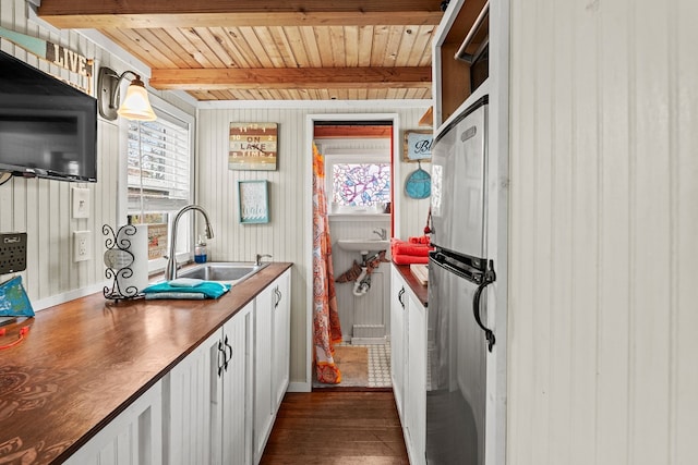 interior space with sink, stainless steel refrigerator, beam ceiling, white cabinets, and wooden ceiling