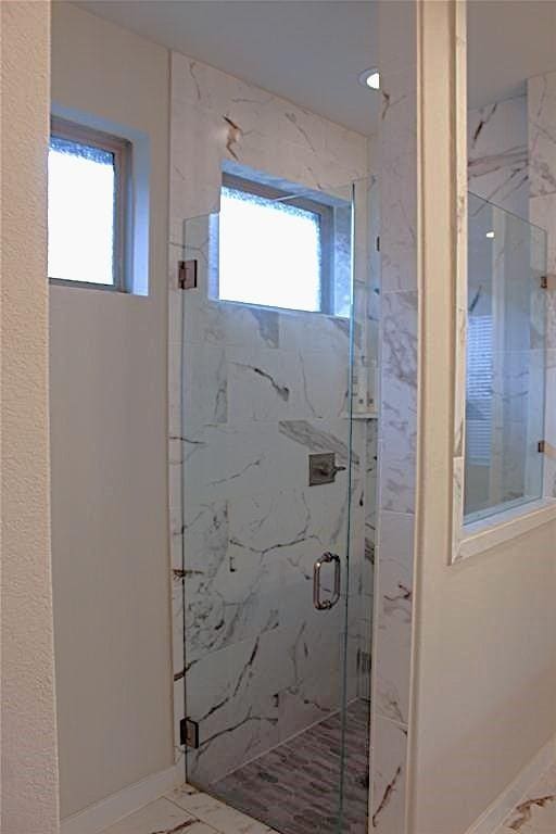 bathroom featuring an enclosed shower and a healthy amount of sunlight