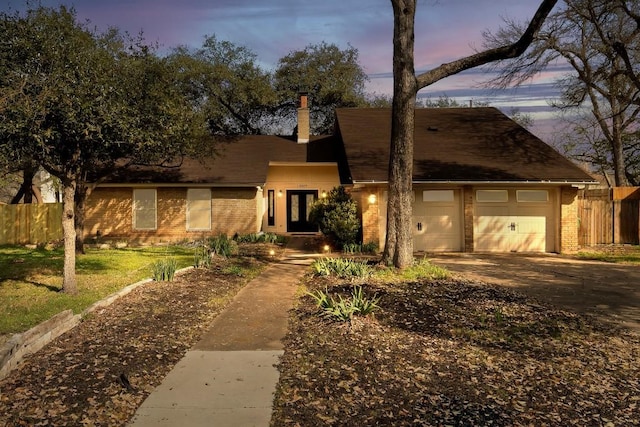 view of front facade featuring brick siding, fence, and driveway