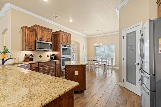 kitchen with sink, appliances with stainless steel finishes, backsplash, ornamental molding, and a kitchen island