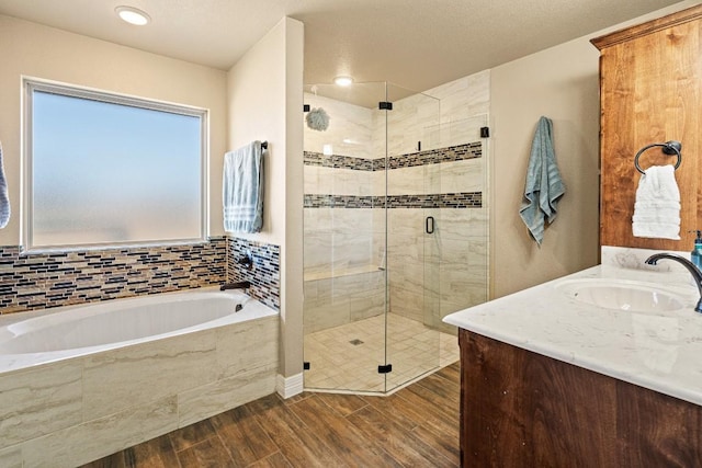 bathroom with wood-type flooring, shower with separate bathtub, and vanity