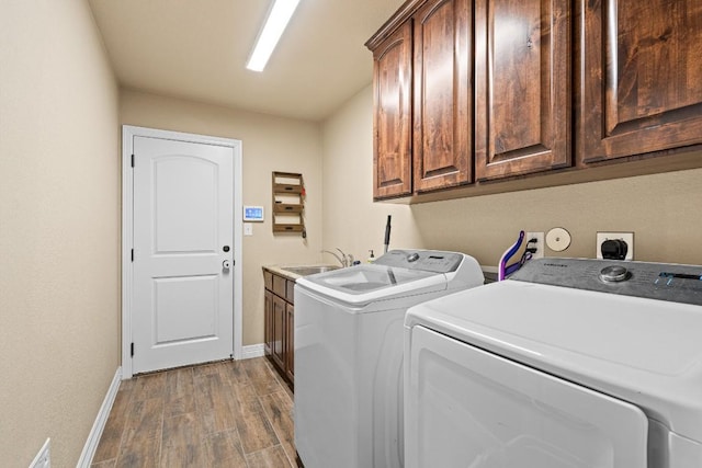 clothes washing area featuring cabinets, washing machine and dryer, hardwood / wood-style flooring, and sink