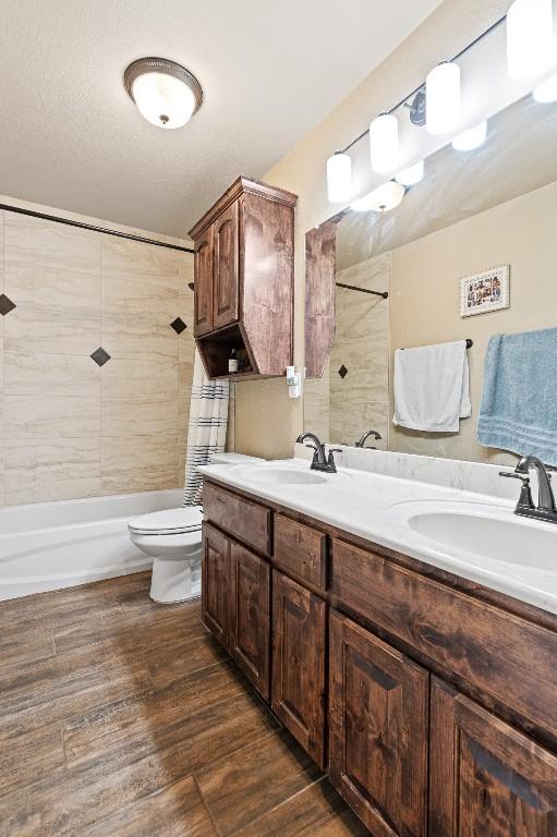 full bathroom featuring vanity, hardwood / wood-style flooring, tiled shower / bath combo, and toilet