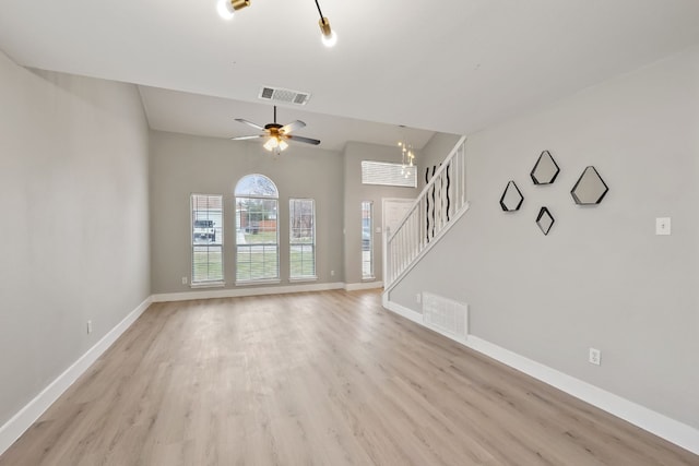 unfurnished living room with ceiling fan with notable chandelier and light wood-type flooring