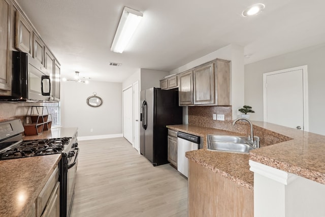 kitchen with light brown cabinetry, sink, decorative backsplash, black appliances, and light hardwood / wood-style flooring