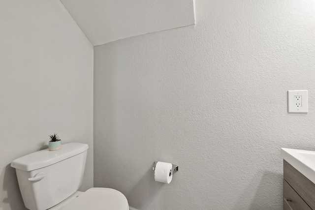 bathroom with vanity, toilet, and vaulted ceiling