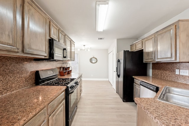 kitchen featuring sink, decorative backsplash, light wood-type flooring, and black appliances