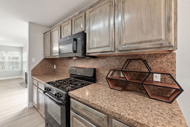 kitchen featuring tasteful backsplash, light stone counters, black appliances, and light hardwood / wood-style floors