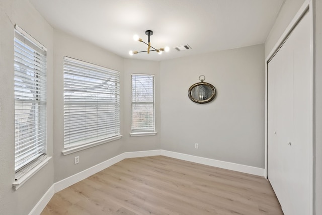 unfurnished dining area with an inviting chandelier and light hardwood / wood-style floors