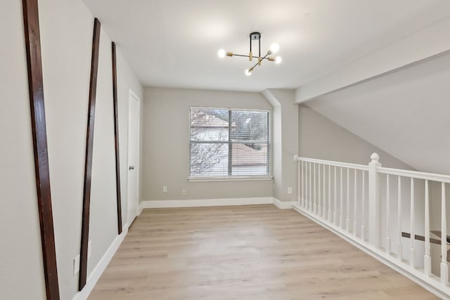 bonus room featuring lofted ceiling, light hardwood / wood-style flooring, and a notable chandelier