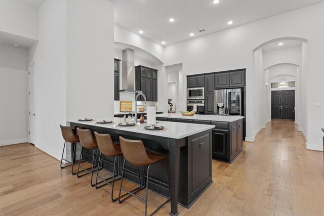 113 University Lands Dr, Liberty Hill, TX 78642 - kitchen with stainless steel appliances, wall chimney exhaust hood, a peninsula, arched walkways, and a kitchen bar